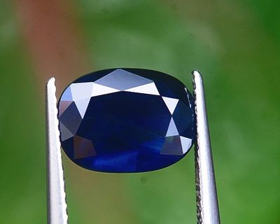 un gros plan d'un diamant bleu tenu par une pince