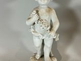a white statue of a boy holding a basket of flowers