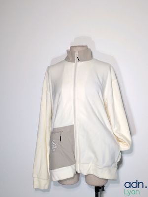 une veste blanche posée sur un mannequin, contre un mur blanc