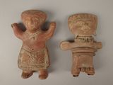 two clay figurines of a man and a woman on a white surface