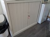 a white cabinet with a door and a trash can next to it
