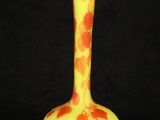 an orange and yellow vase sitting on top of a black table