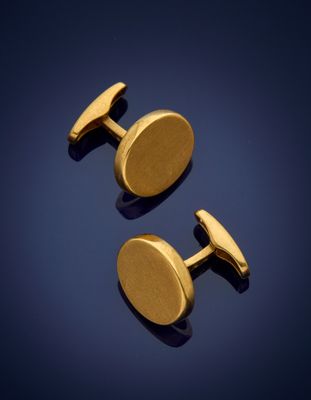 a pair of gold cufflinks on a blue background