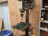 une perceuse posée sur une table dans un atelier, à côté d'un seau bleu