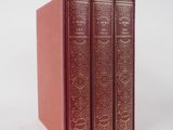 trois livres rouges superposés sur une surface blanche