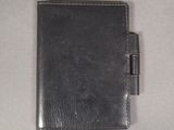 leather wallet with pen on top of it on a white surface