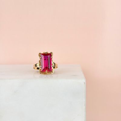 a close up of a pink tourmaline ring sitting on a white block