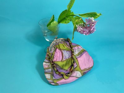 a vase with a flower and a purse on a table