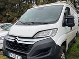 La camionnette blanche est garée dans l'herbe, à côté d'autres voitures.