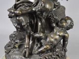 bronze statue of a woman holding a child on a rock