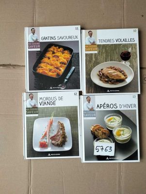 four cookbooks of various types of food are on a cardboard box