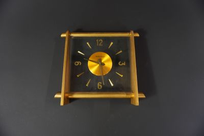 a gold clock on a black wall with a black background