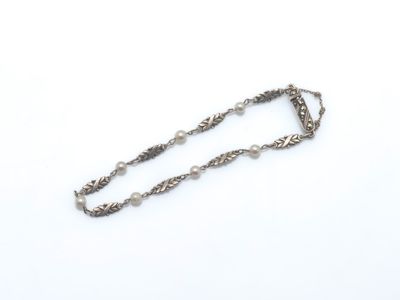 une chaîne en argent ornée de perles, posée sur un fond blanc