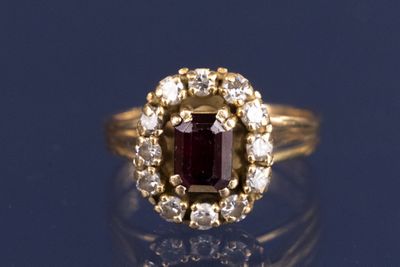 une image d'une bague avec une pierre rouge entourée de diamants blancs
