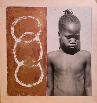 une vieille photo d'un jeune garçon torse nu, debout à côté d'un tableau représentant des cercles