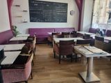de nombreuses tables et chaises dans un restaurant, avec un tableau noir accroché au mur