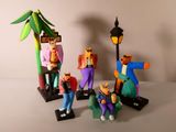 Plusieurs figurines représentant des personnages vêtus de habits colorés sont disposées près d'un lampadaire.