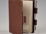 wallet with pen and notepad in it sitting open on a table