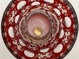 a red and white bowl with a gold heart in it