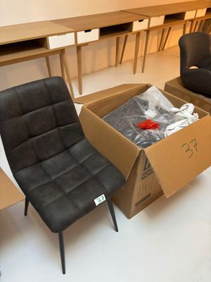 deux chaises et une table dans une pièce où se trouve un carton posé par terre