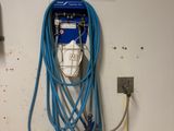 a blue hose attached to a wall next to an electrical outlet