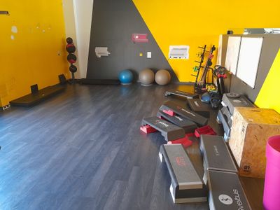 une salle de sport équipée d'une grande variété d'appareils de musculation disposés sur le sol