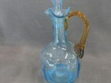 a blue glass vase with a gold handle on a table