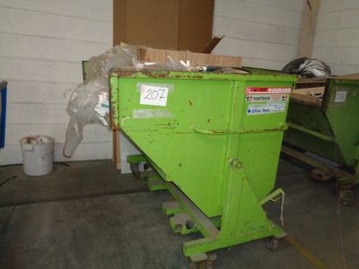 a green dumpster sitting in a room with a lot of boxes