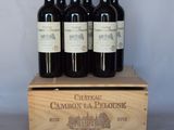 quatre bouteilles de vin se trouvent dans une caisse en bois posée sur une table