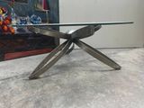une table en verre avec des pieds en métal et un plateau en verre