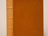 un vieux livre posé sur une table blanche à côté d'un mur blanc