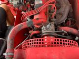 a man working on the engine of a red truck