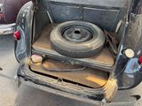 an old car with a flat tire in the back of it
