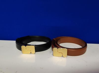 deux ceintures ornées de boucles dorées posées sur une table blanche