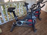 two stationary exercise bikes on a wooden floor in a room