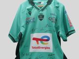 un gros plan sur un maillot vert portant des signatures