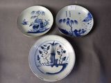 trois assiettes bleues et blanches ornées de motifs orientaux, posées sur une table