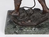 bronze statue of a boy with a rope on a rock