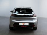 the rear end of a silver car in a room with a white wall