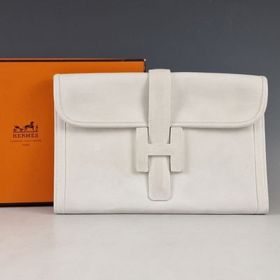 une photo d'un sac à main blanc posé sur une table, à côté d'une boîte orange