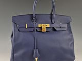 un sac à main en cuir bleu muni d'un fermoir doré sur la poignée