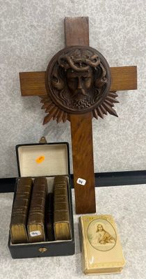 une croix en bois et une boîte de livres posées par terre