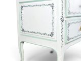 a small white chest of drawers on a white background