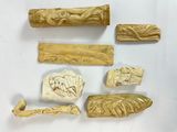 Plusieurs pièces de bois sculpté sont exposées sur un fond blanc