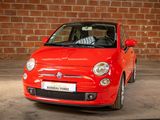 a small red car that is parked in front of a brick wall