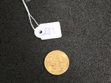 une petite pièce d'or sur laquelle est collée une étiquette indiquant son prix