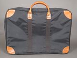 an image of a black suitcase with a brown handle on a gray background