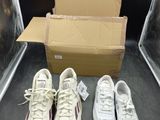 trois paires de baskets blanches sont posées à côté d'une boîte