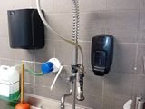 a kitchen sink with a faucet, soap dispenser, and a soap dispenser on the wall