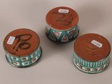 three ceramic containers sitting on top of a table with labels on them